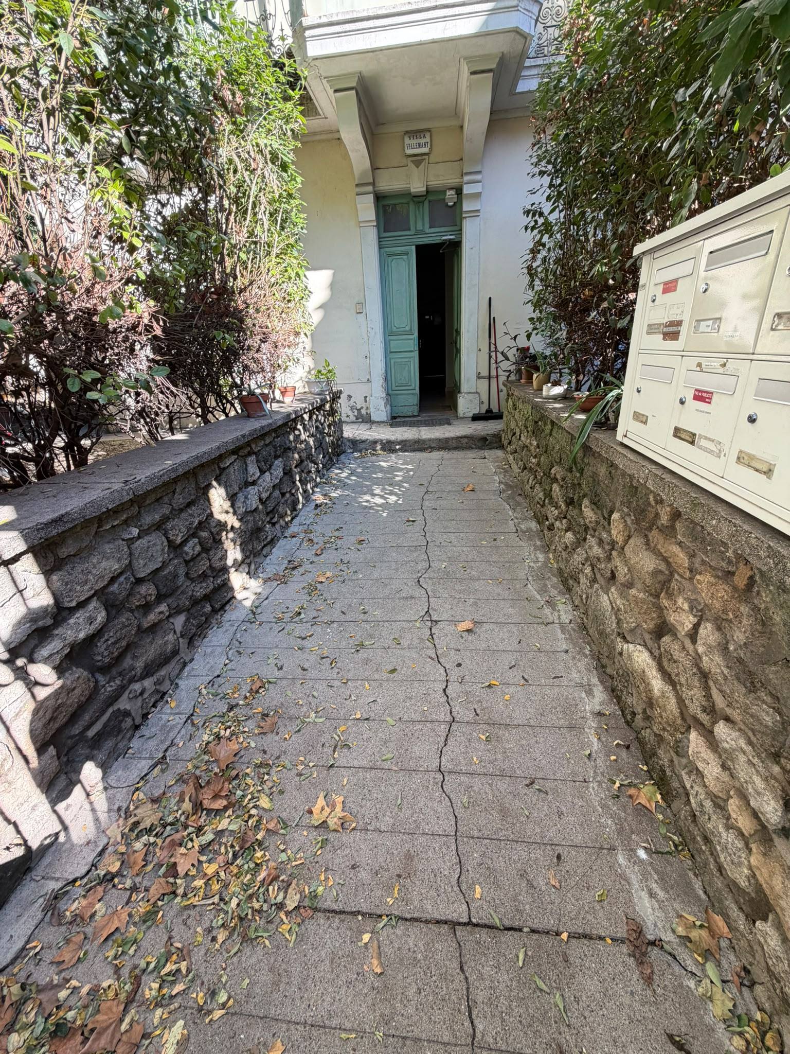 Avant : allée d'entrée d'un immeuble couverte de feuilles mortes et de saletés à Montpellier